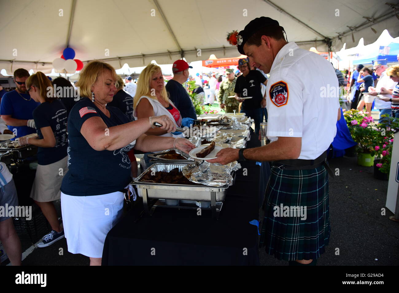 New York City, United States. 25th May, 2016. FDNY Emerald band member gets BBQ plated. The 28th annual NYC Fleet Week brought US navy & coast guard ships to the Brooklyn Ferry Terminal in Red Hook where sailors, guard & marines were greeted with entertainment, awards & hearty bbq plates. Credit:  Andy Katz/Pacific Press/Alamy Live News Stock Photo