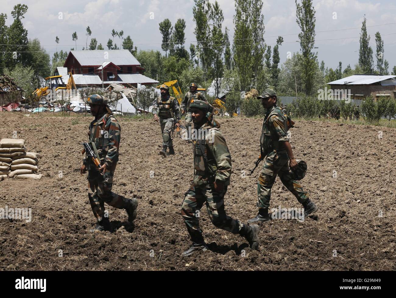 Srinagar, Indian-controlled Kashmir. 27th May, 2016. Indian army troopers walk back to their base camp after a gunfight at Khonchipora village in Tangmarg, some 35 kilometers north of Srinagar, summer capital of Indian-controlled Kashmir, May 27, 2016. Six militants and an Indian military trooper were killed in two separate gunfights in restive Indian-controlled Kashmir, officials said Friday. Credit:  Stringer/Xinhua/Alamy Live News Stock Photo