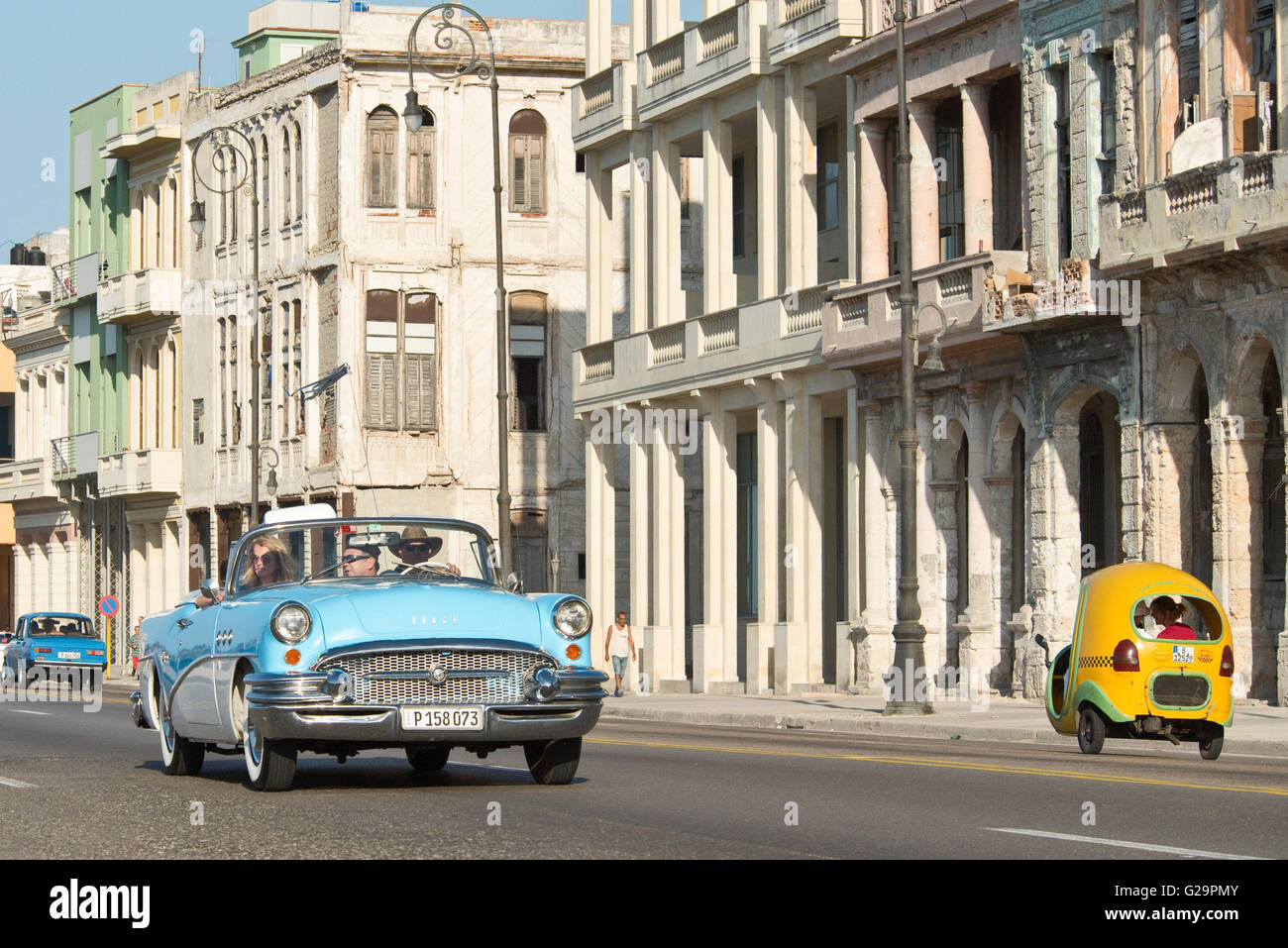 A compressed perspective view of a 1955 Buick Special Convertible and a Coco taxi travelling along the Malecón in Havana, Cuba. Stock Photo