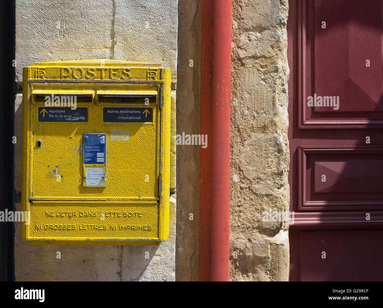 French yellow metal mailboxes on stone wall in a street of Aquitaine. France. Stock Photo