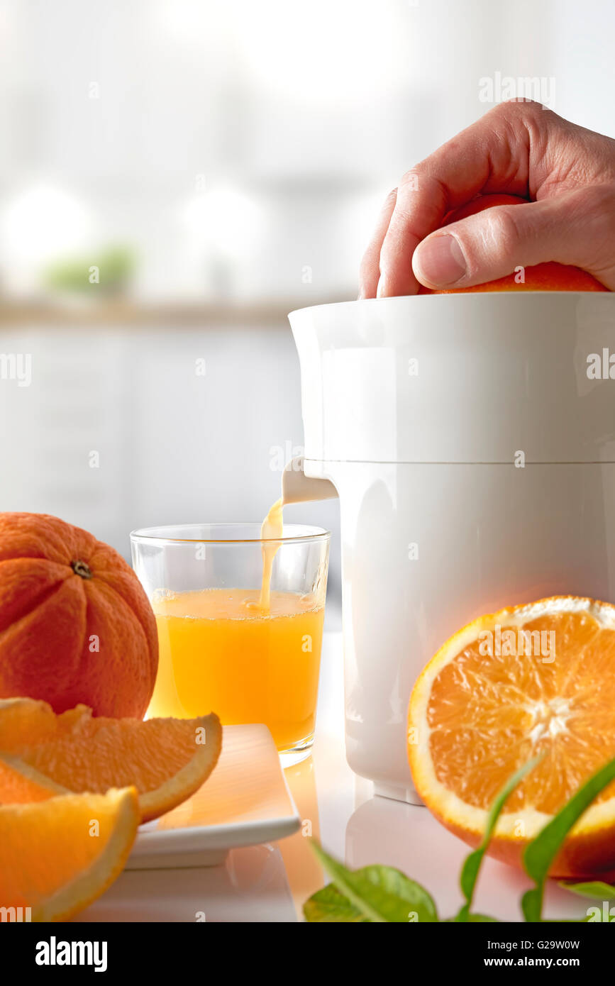 Female hand squeezing orange juice from fresh oranges with a juicer in the  home kitchen, ?lose up Stock Photo - Alamy