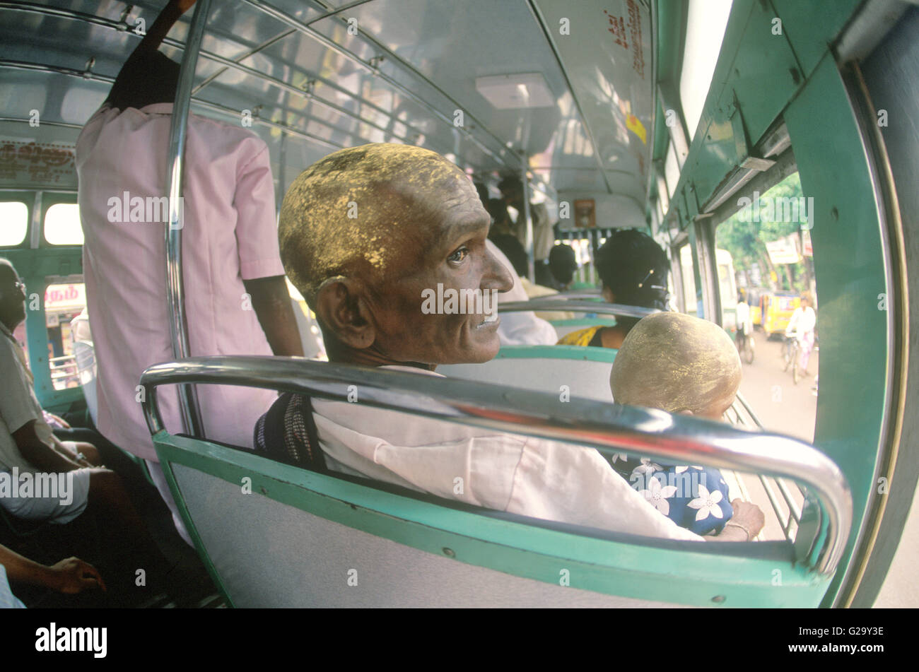 A father and son sit on a public bus with with sandalwood paste over their shaven heads after doing puja at Ranganathaswami. Stock Photo