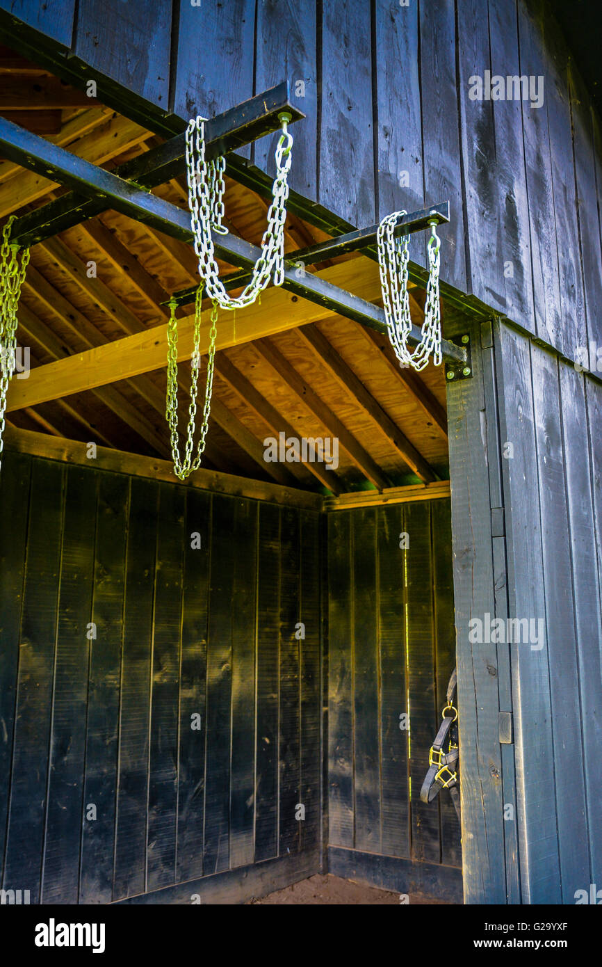 An Open Sided Wooden Horse Stable Painted Black Holds Metal