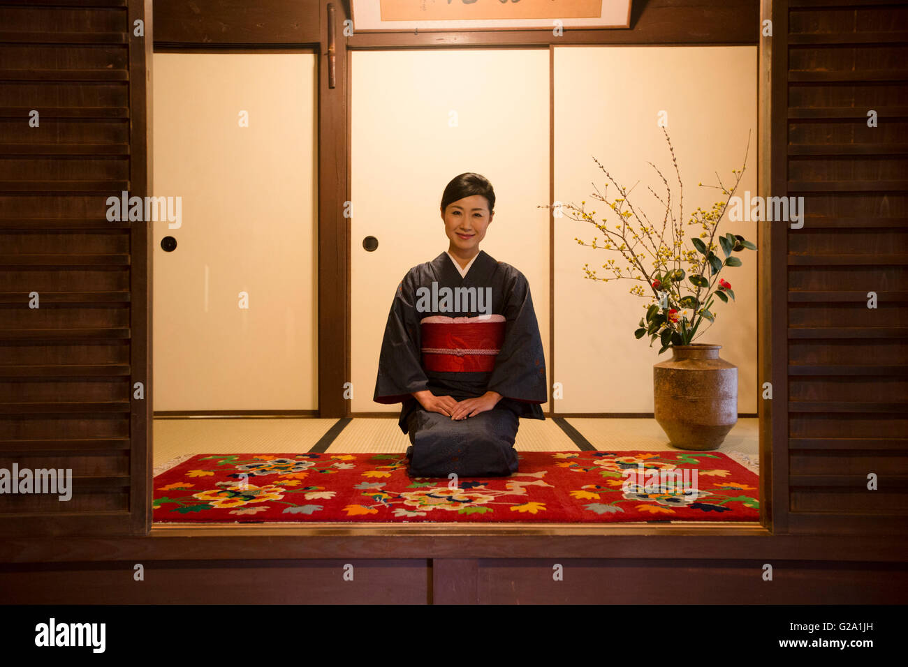 Mid Adult Japanese woman in kimono sitting Stock Photo