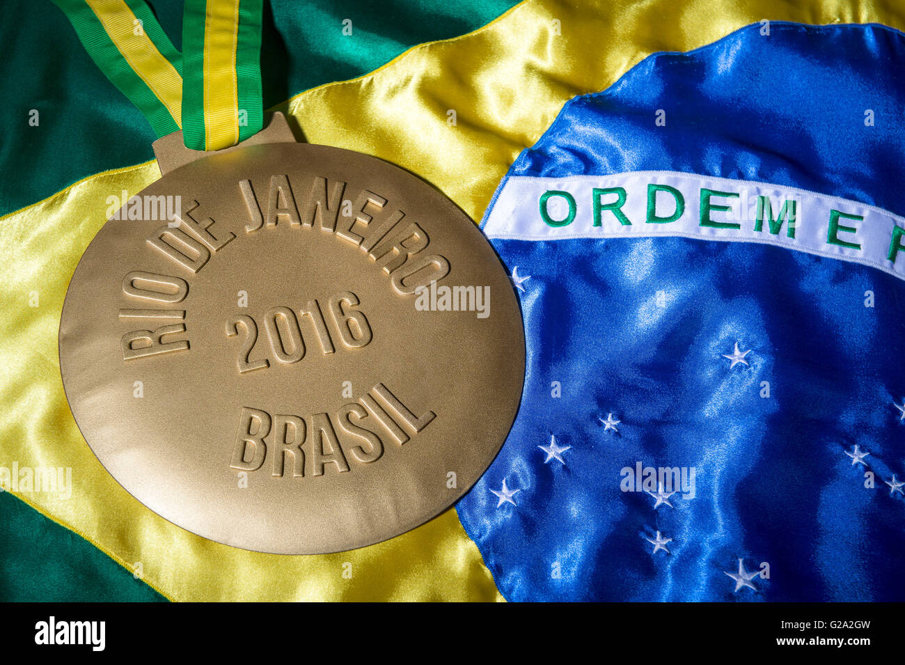 RIO DE JANEIRO - FEBRUARY 3, 2016: Large gold medal commemorating the 2016 Olympiad (Olympic Games) sits on Brazil flag. Stock Photo