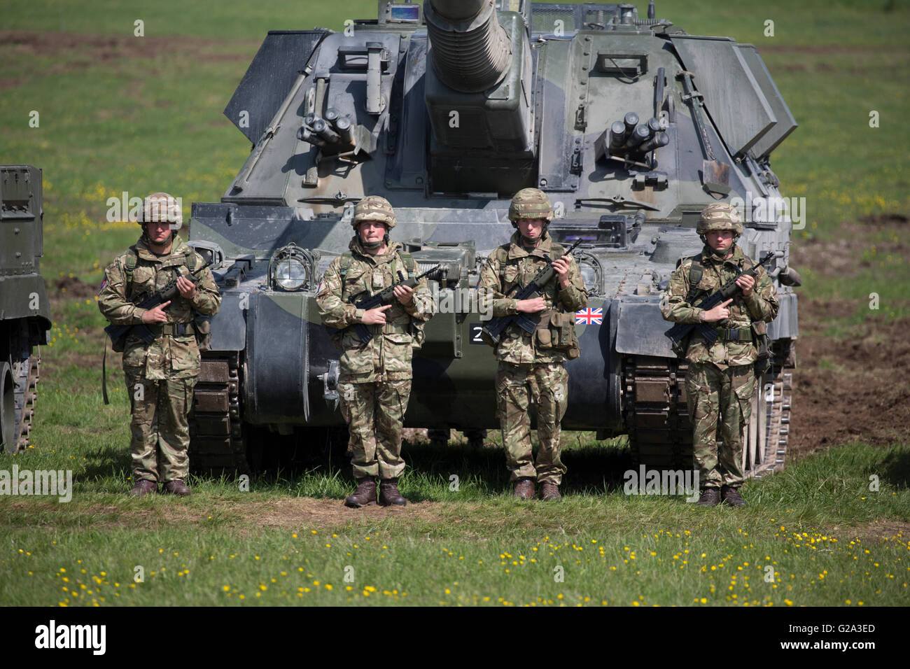 Four soldiers of the Royal Artillery Regiment stand on guard in front of a AS90 self propelled Gun on Salisbury Plain, Wiltshire Stock Photo