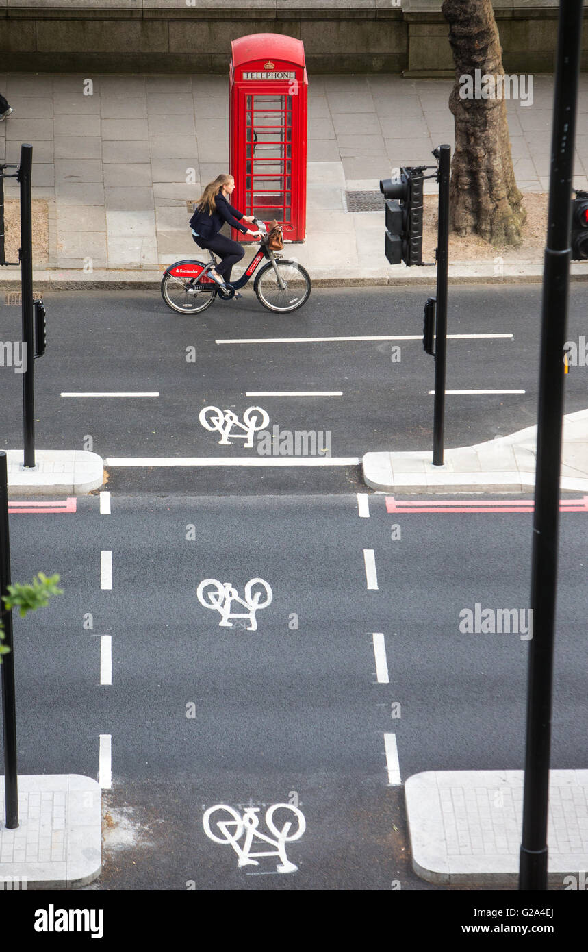 An aerial view of a cyclist in a cycle lane passing a red phone box with three cycle signs on the embankment in London Stock Photo