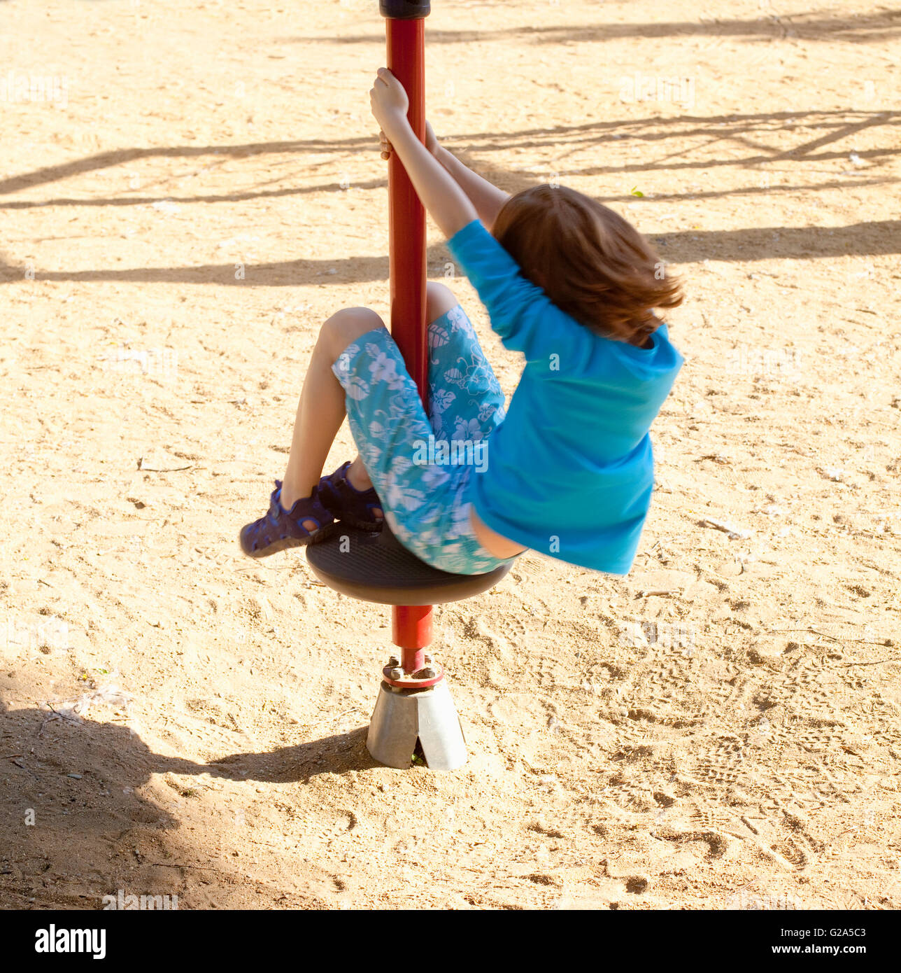 Boy with Blond Hair Spinning on a Pole at Playground Stock Photo - Alamy