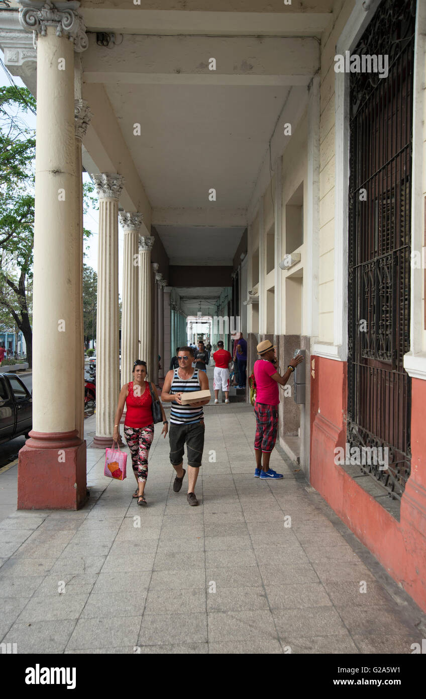 Cubans walking through a colonnaded passageway on a street in Cienfuegos Cuba Stock Photo