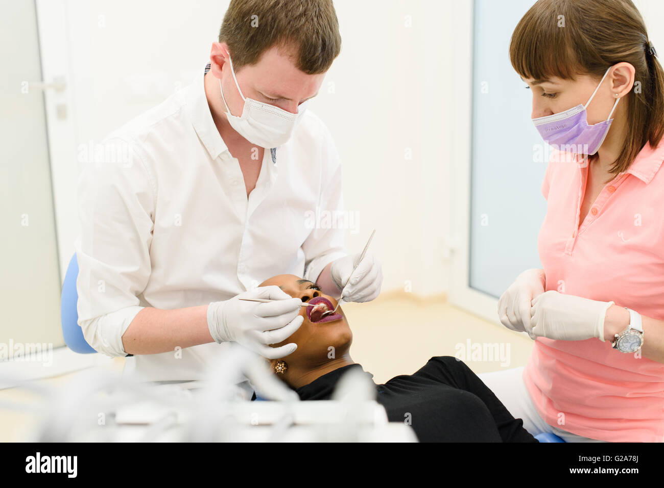 Black American or African female patient with dentist, assistant in a