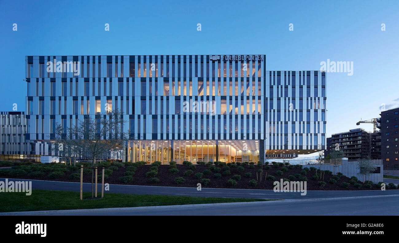 Distant view at dusk with lit interiors. Fornebuporten, Oslo, Norway. Architect: DARK, 2015. Stock Photo