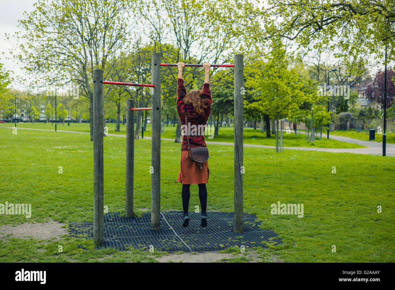 A young woman is doing pull ups in a park Stock Photo Alamy