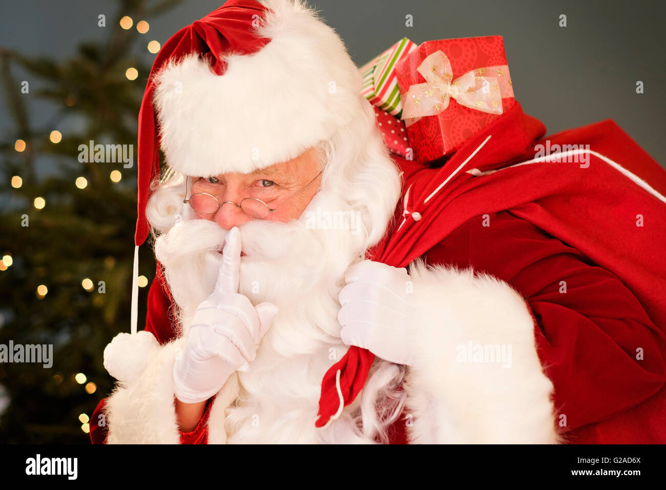 Portrait of Santa Claus with finger on lips, carrying sack over shoulder Stock Photo