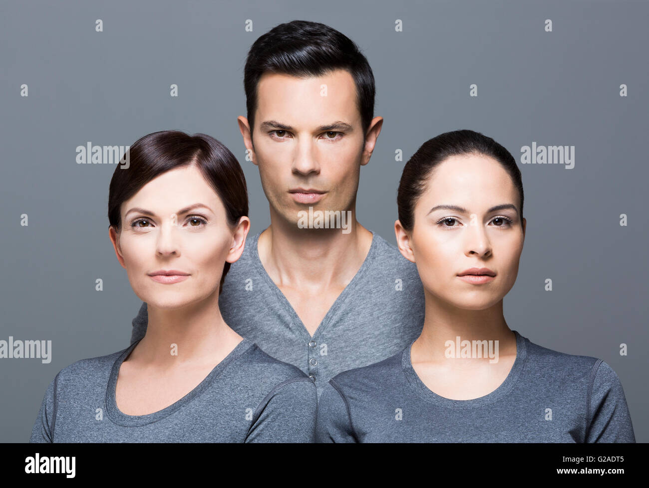 Man and two women wearing grey tops Stock Photo