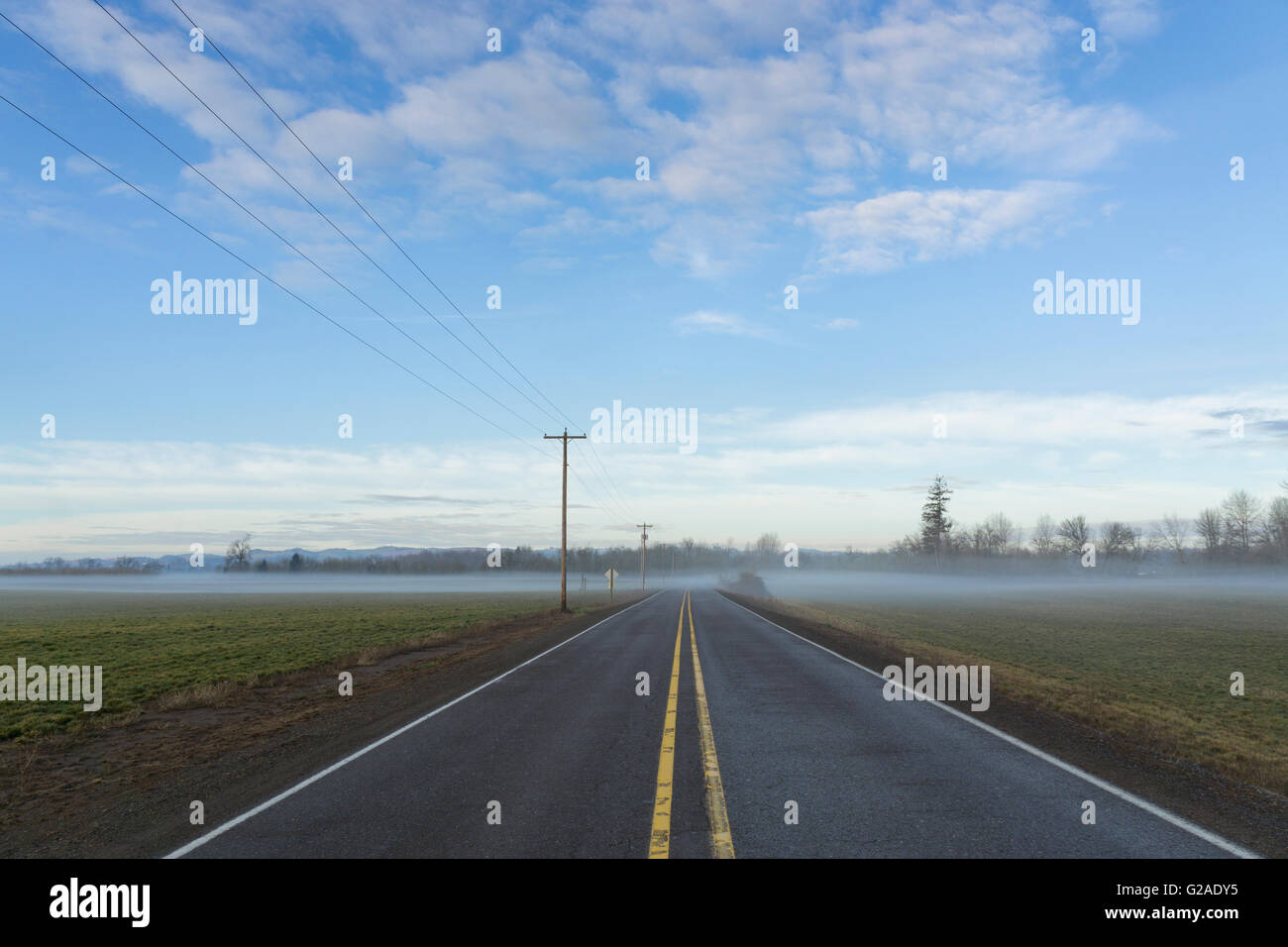 Highway going through plain covered with fog Stock Photo