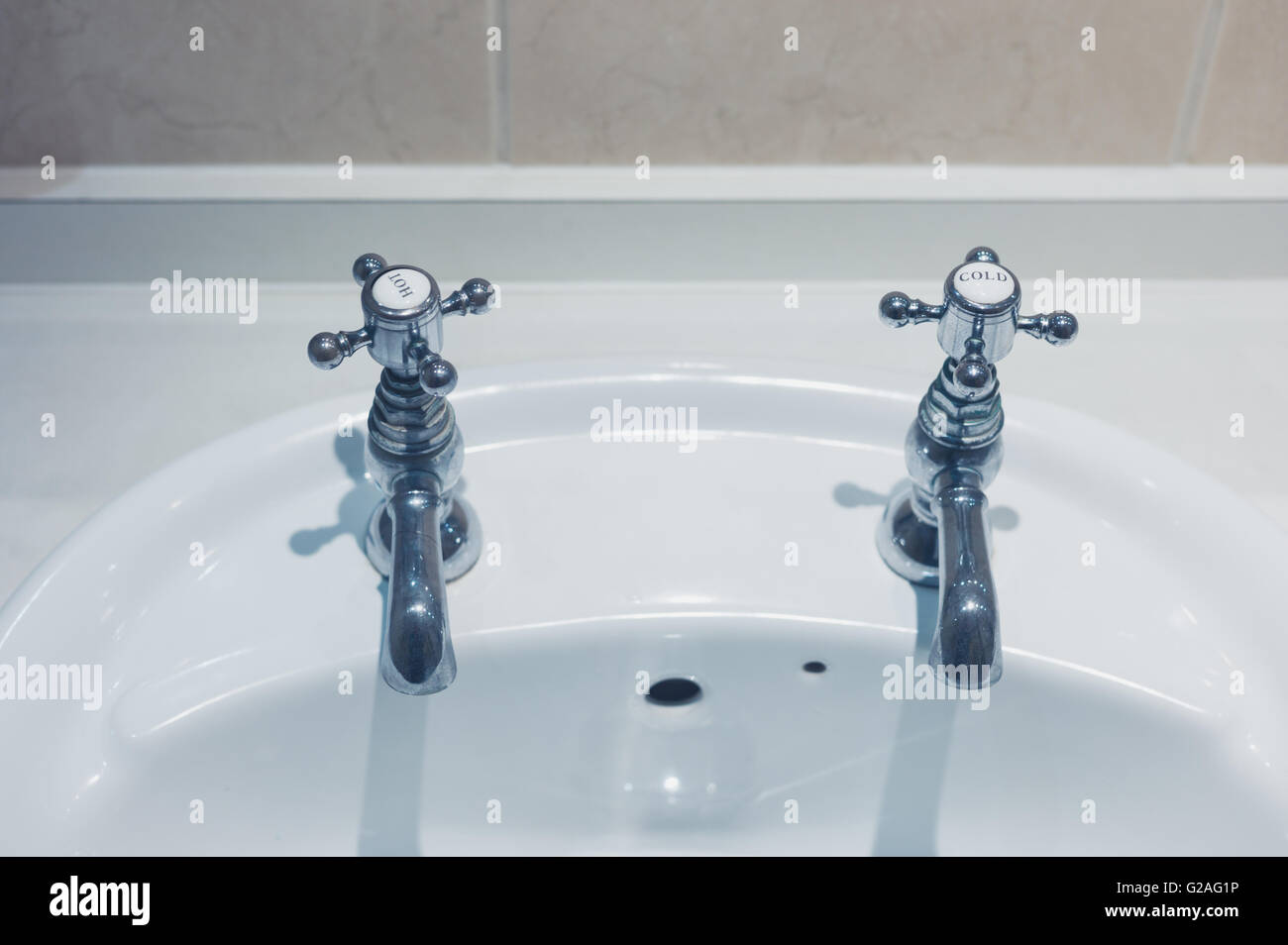 A hot and cold tap and a wash basin in a bathroom Stock Photo