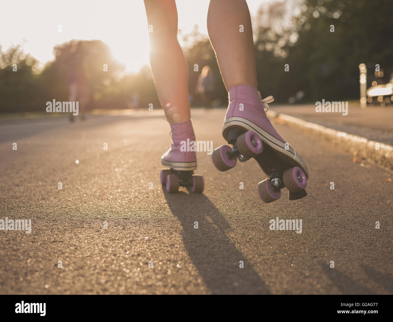 The legs of a young woman as she is roller skating in a park at sunset