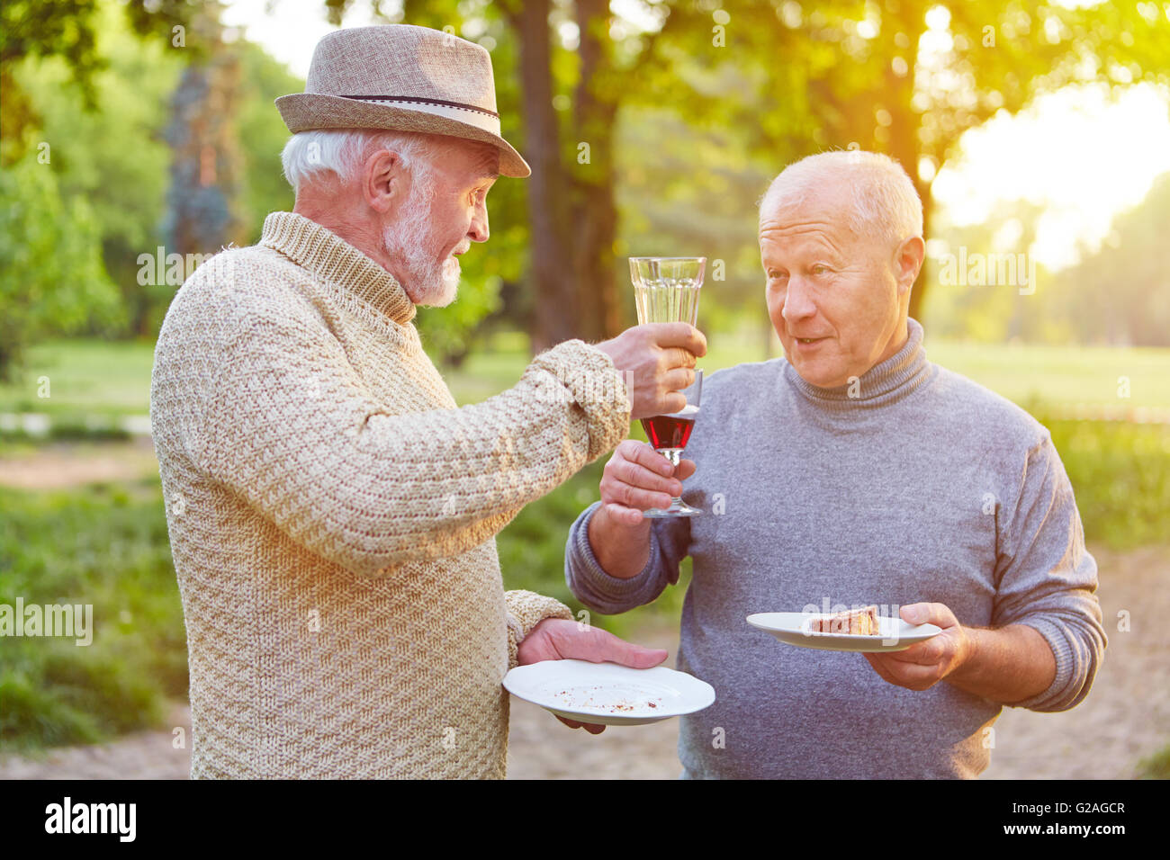 Two senior men at a birthday party cheering with glass of red wine Stock Photo