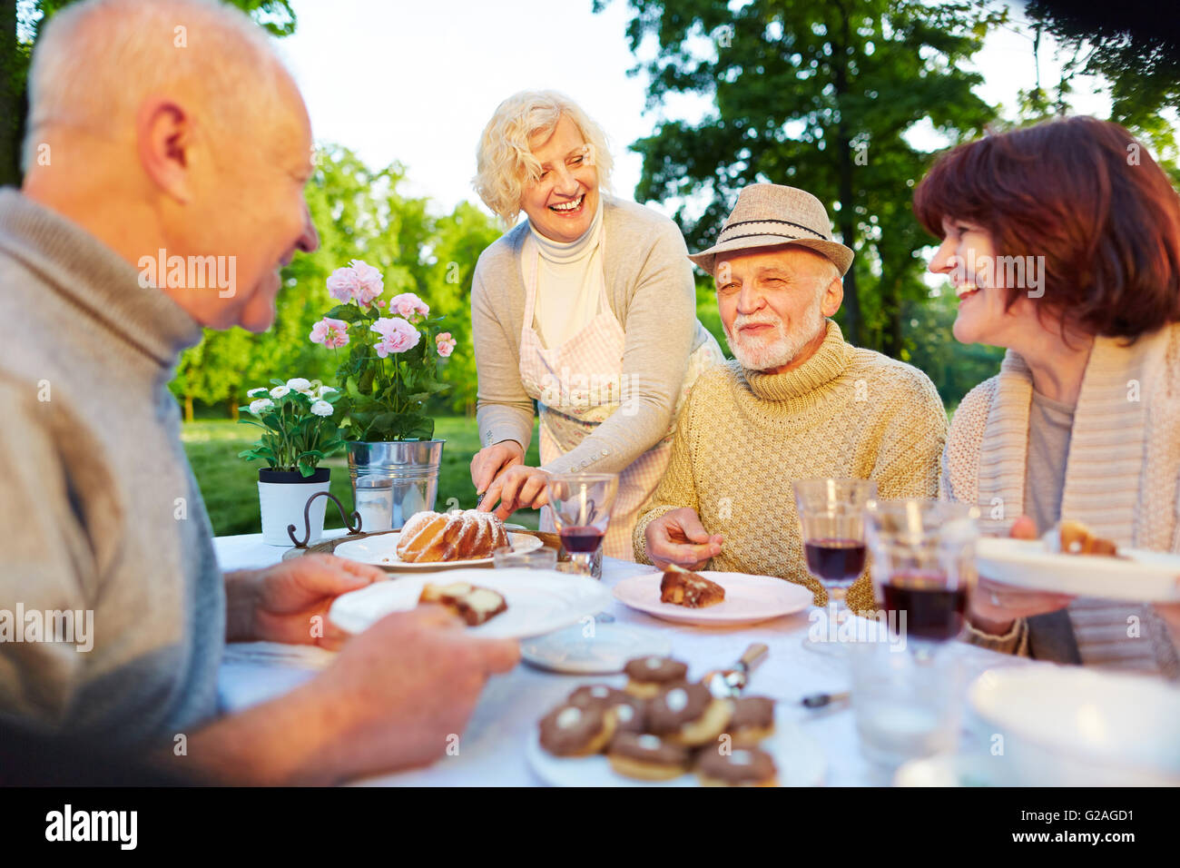 Happy seniors at birthday party sitting with cake in the garden Stock Photo