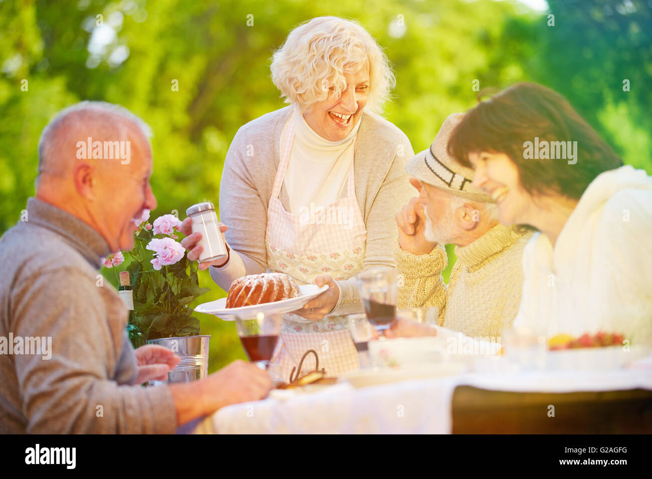 Friends and senior people celebrating birthday with cake at garden party Stock Photo