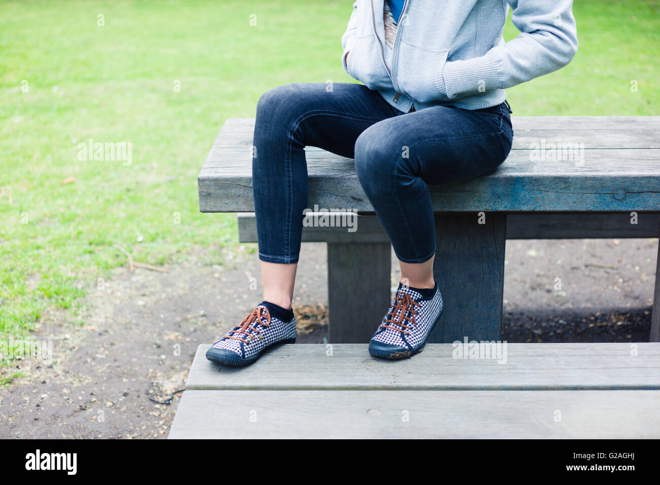 A young woman is sitting on a table in a park Stock Photo - Alamy