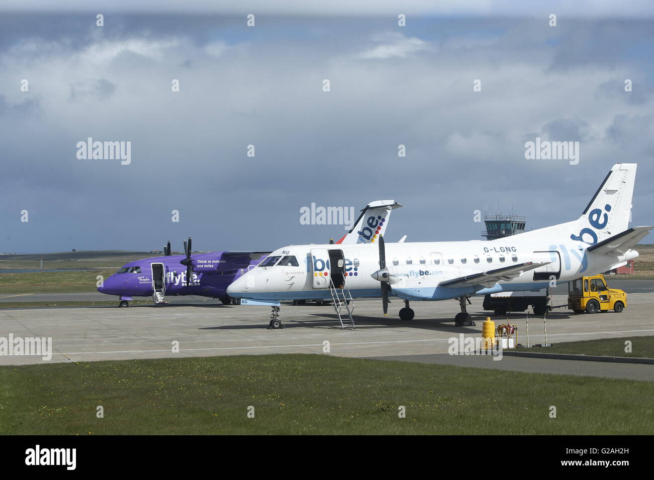 A Dornier 328 painted in the purple colours of Loganair, a Flybe franchise partner, and a Loganair G-LGNG (Saab 340 - MSN 327) at Kirkwall airport. Stock Photo