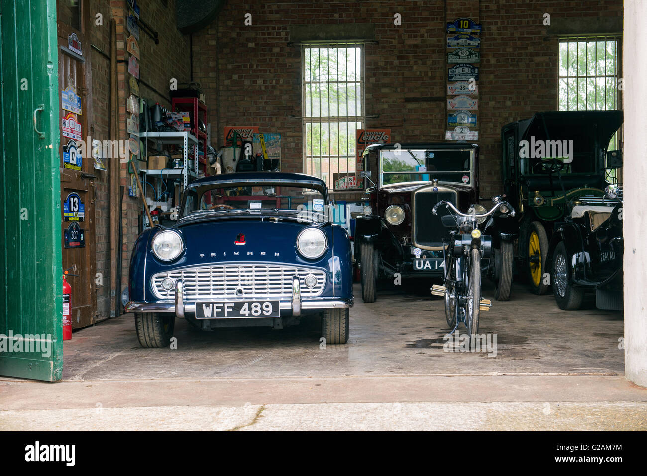 1958 Triumph TR3 and other classic cars in a garage at Bicester Heritage Centre. Oxfordshire, England Stock Photo
