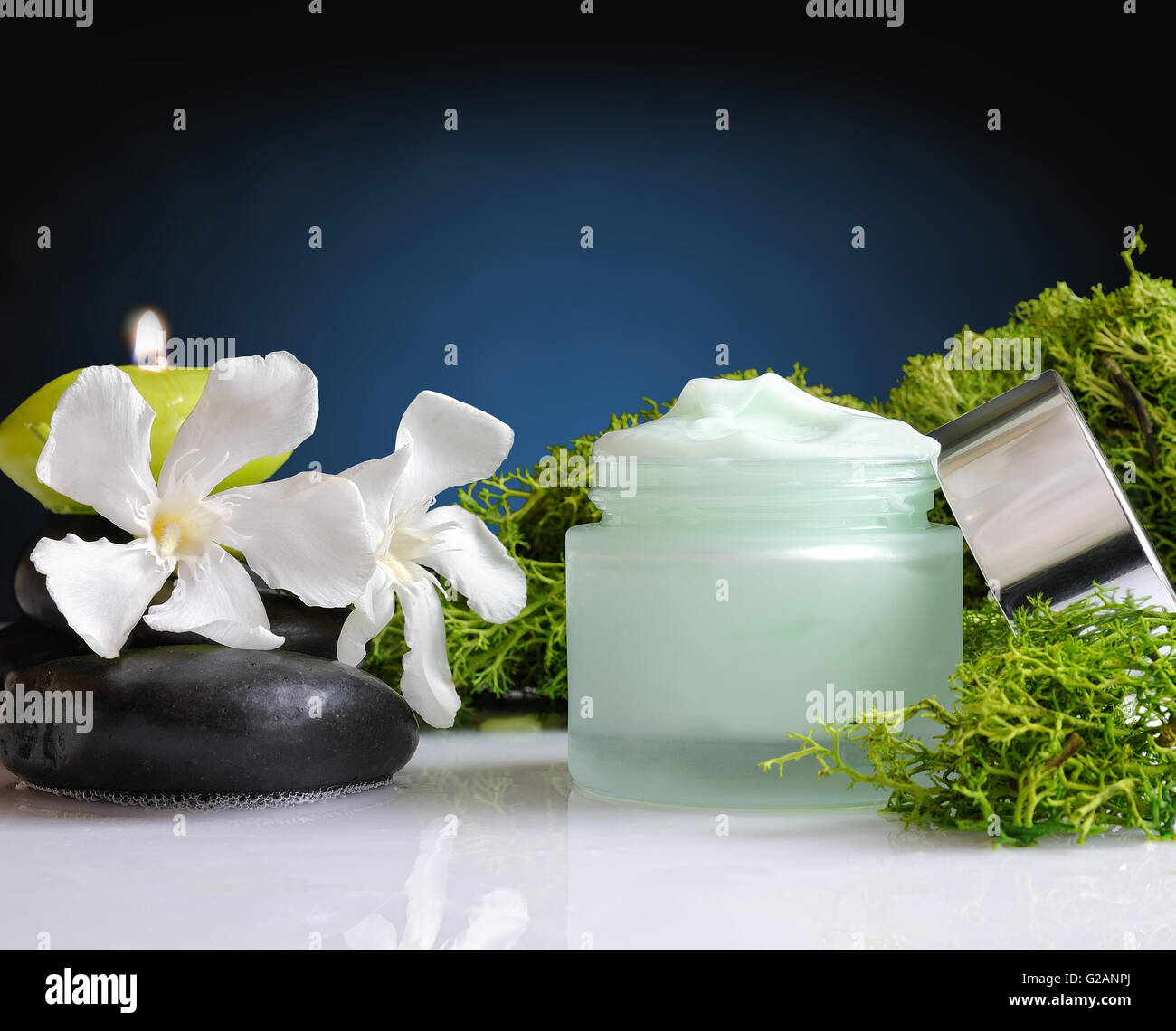 Glass cream jar open algae. Flowers, black stones and seaweed