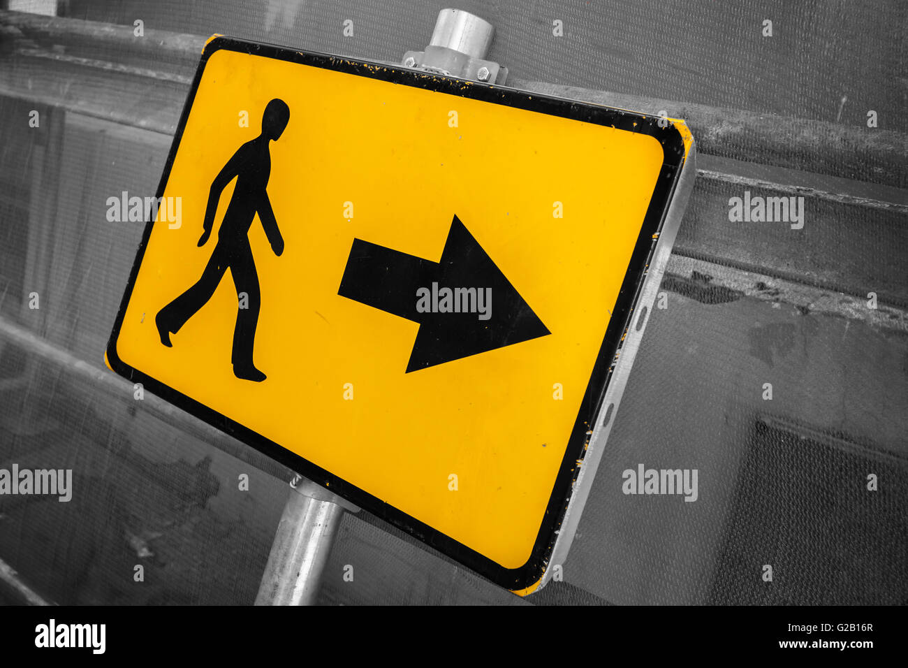 Pedestrians bypass direction. Yellow road sign on construction site fence Stock Photo