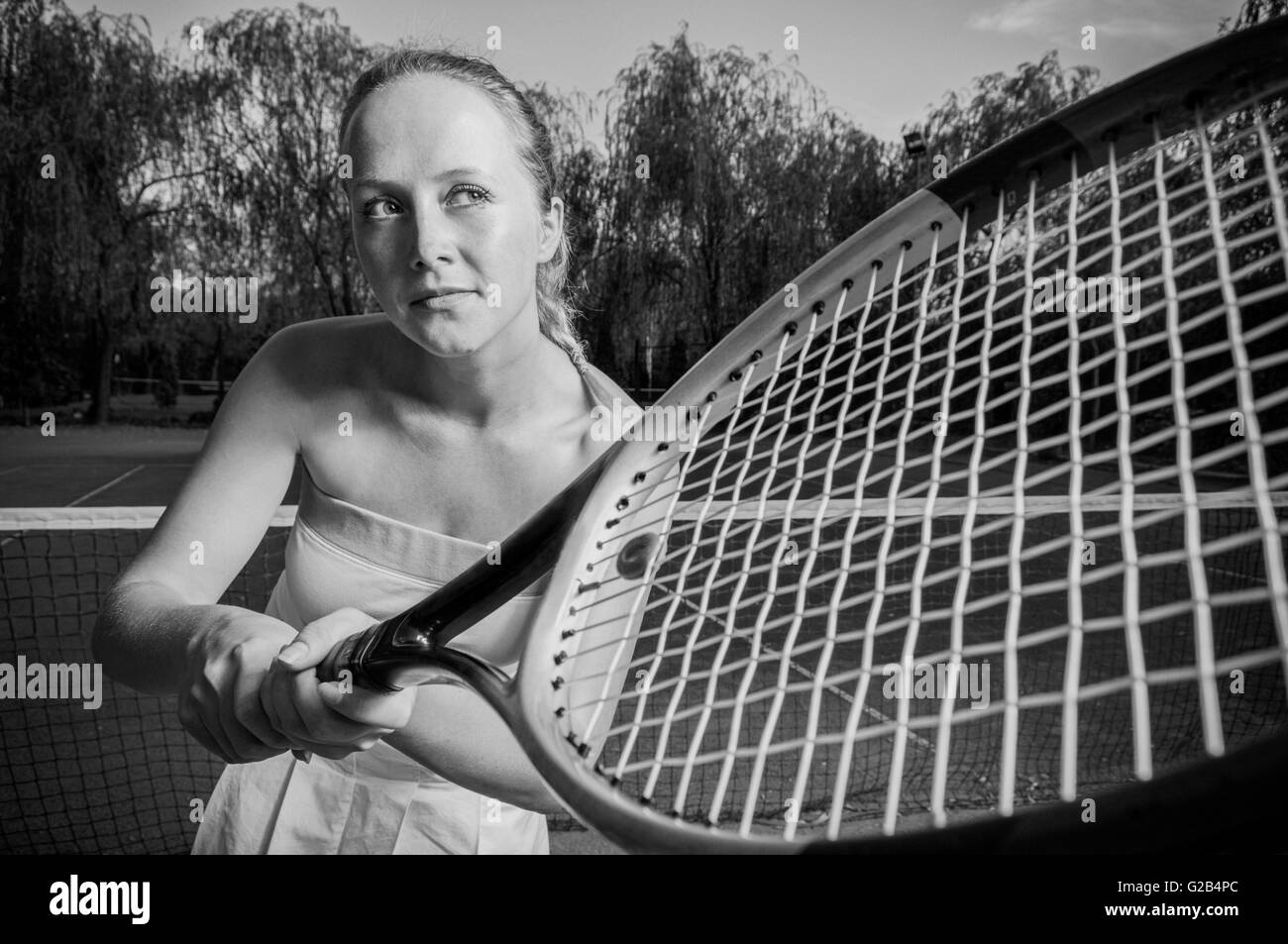 Woman with a tennis racket over her face. Neutral face and confident look.  Close up shot, sport portrait on black Stock Photo - Alamy