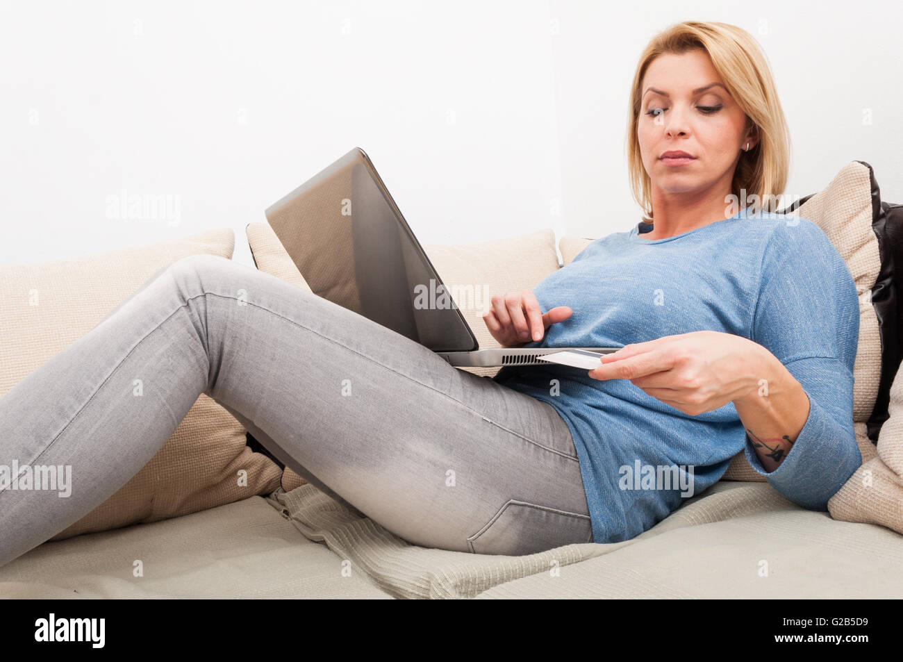 Woman using credit card for shopping online relaxed at home on sofa or couch Stock Photo