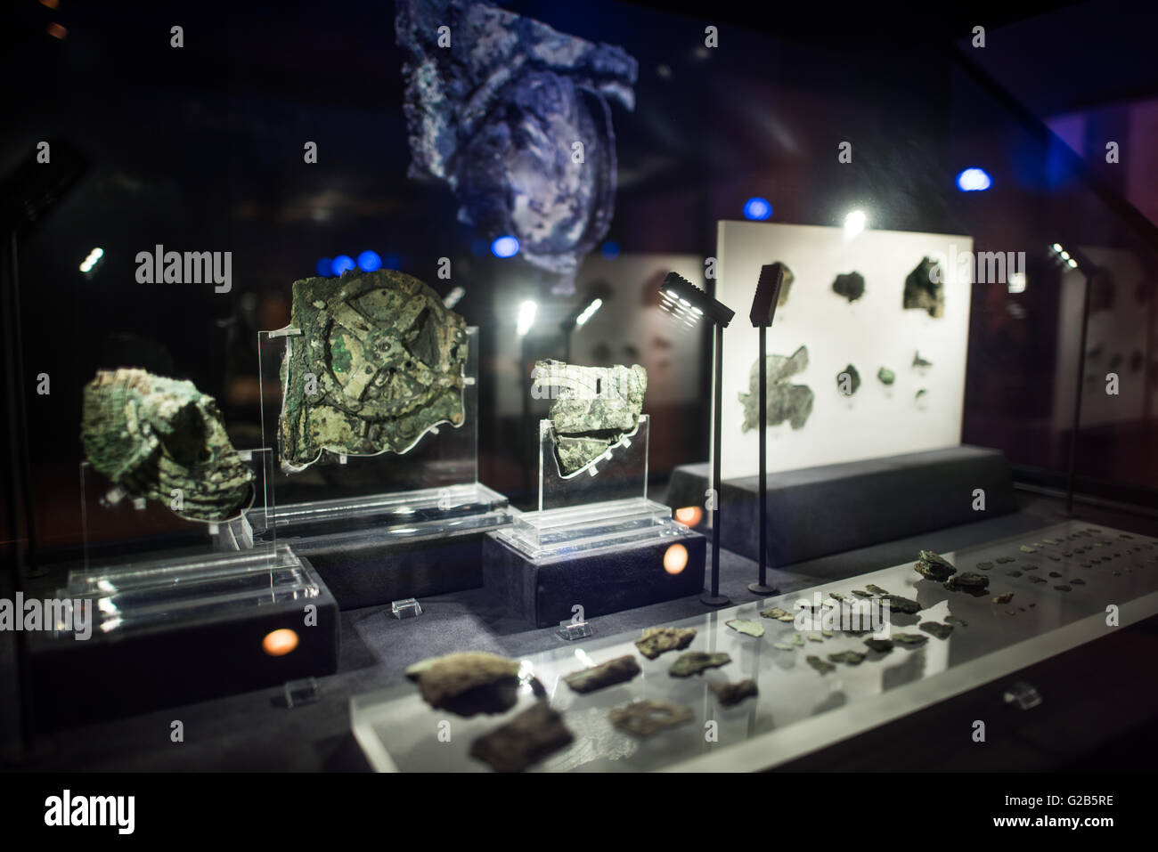 Antikythera Mechanism Fragments National Archaeological Museum Athens // ATHENS, Greece — Original fragments of the Antikythera Mechanism on display at the National Archaeological Museum in Athens, Greece. In the foreground are the 75 small fragments. The largest piece to the left in the back, with the circular gear clearly visible, is known as Fragment A and contains most of the Mechanism's gears. The ancient Greek astronomical calculator, discovered in a shipwreck in 1900, dates to between 100 BC and 205 BC. The corroded bronze fragments represent the world's oldest known complex astronomica Stock Photo