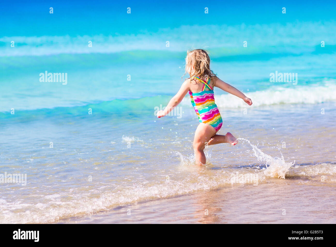 Маленькая кудрявая девочка на пляже