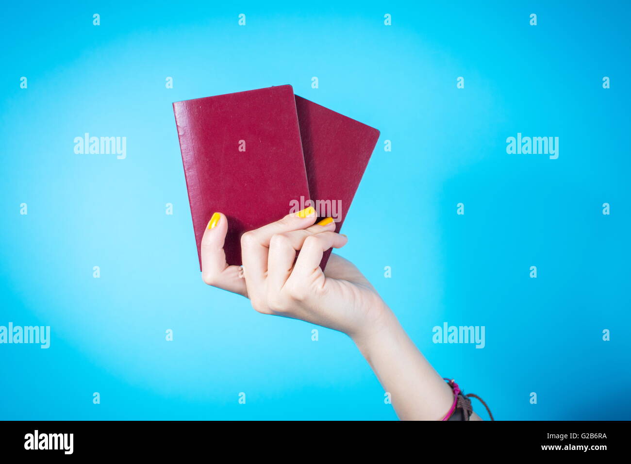 Womans hand holding a two red passports against blue background Stock Photo