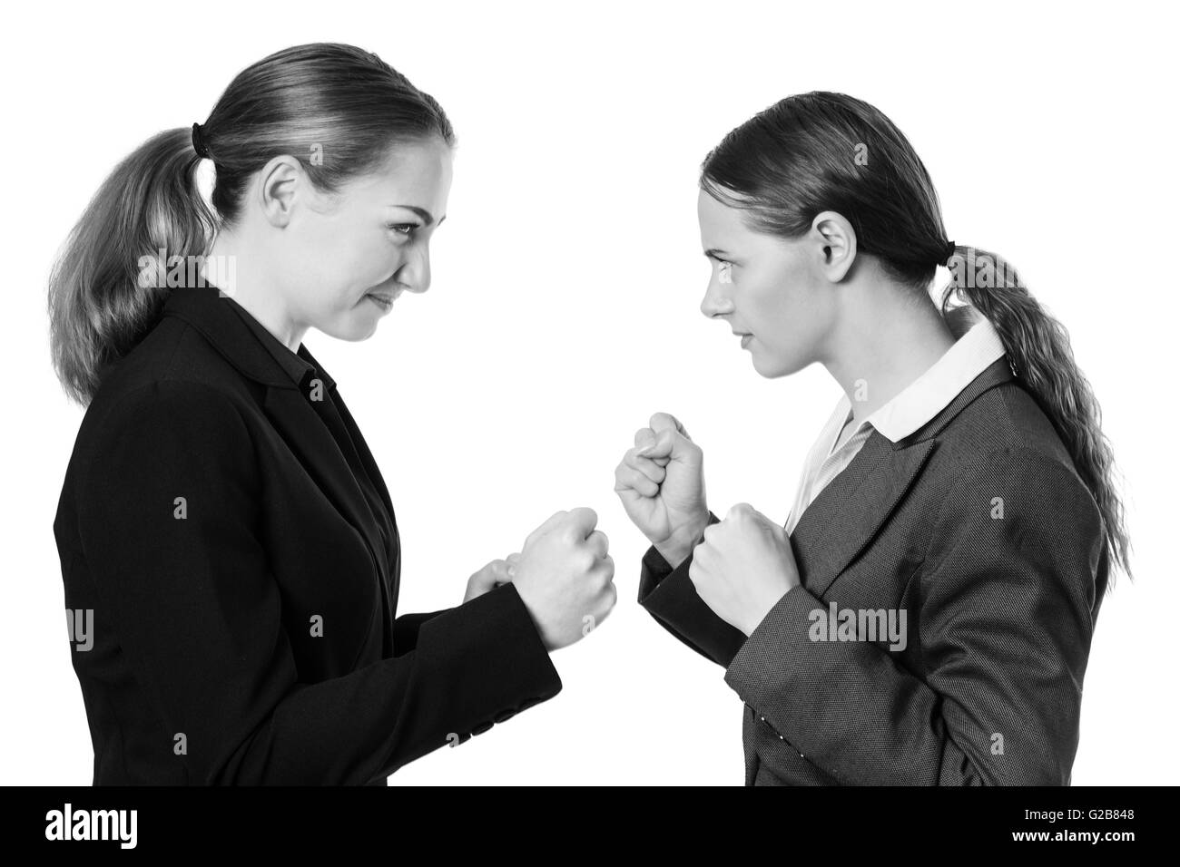 Studio shot of two business women with their fists raised, ready for a fight. Isolated on White. Stock Photo