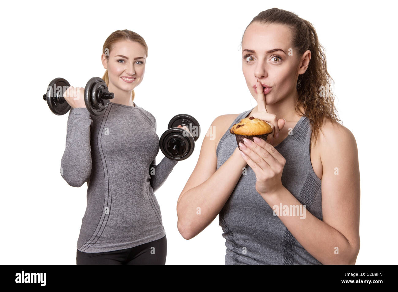 Two Sporty Women Holding Muffin And Dumbbells On White Background Stock Photo