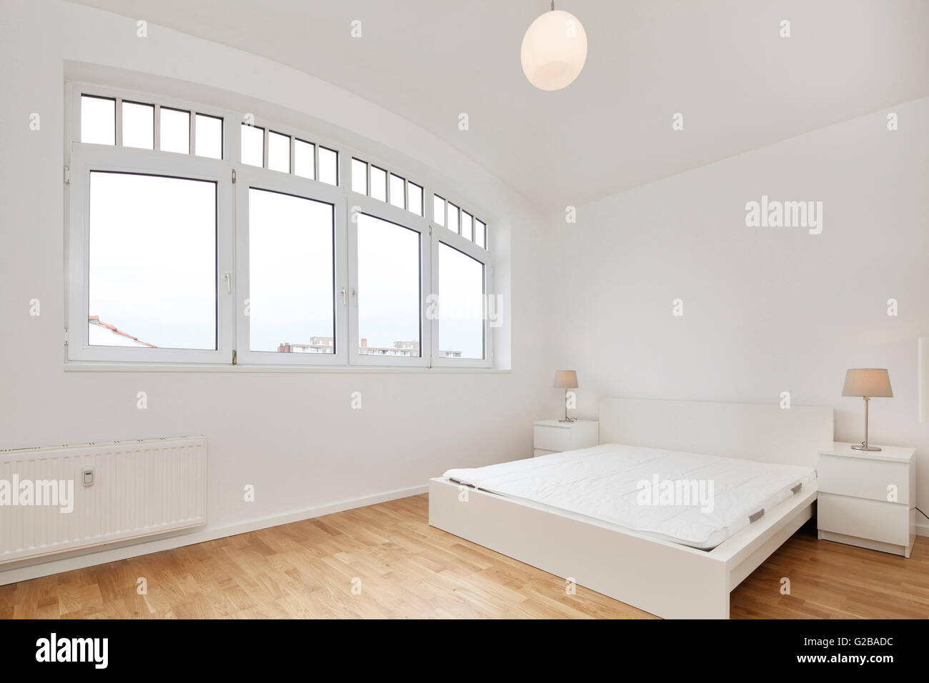 Conversion of Dach or Loft Space in Reichenberger Strasse, Kreuzberg. View of a modern bedroom with large wide windows. Contemporary furniture and minimal decoration. White walls and wood floors. Stock Photo