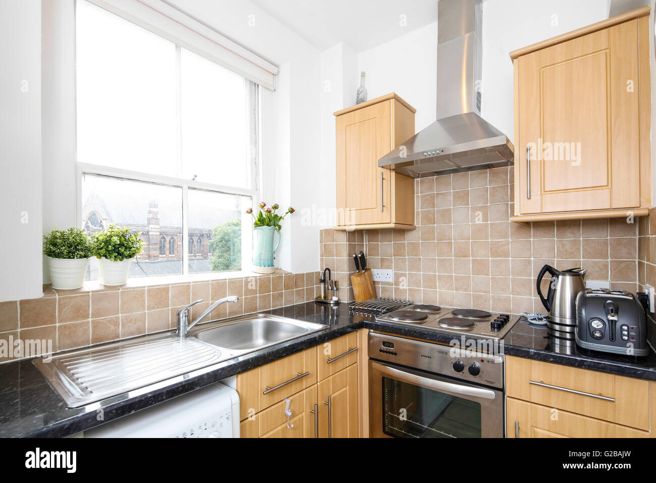 Park House, Harrington Road. Modern kitchen with fresh wood cabinets and black countertops. Large window over sink. Stock Photo