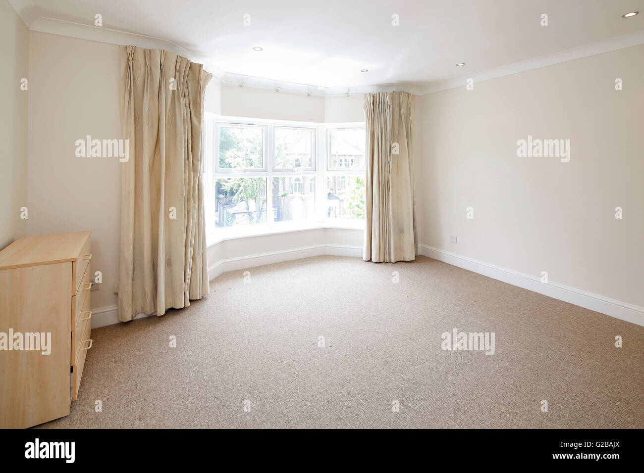 Pavilion Court, Hampstead. View of an empty room apart from a dresser. Large windows with pulled back curtains. Stock Photo