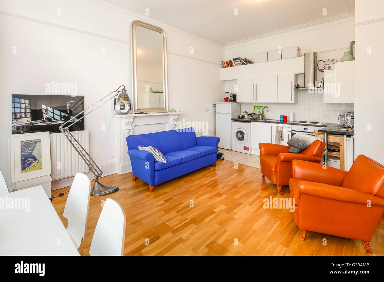 Pembridge Square, Notting Hill. Open plan living and dining room. Colourful contemporary couch and chairs. Wood floors and modern floor lamp. Stock Photo