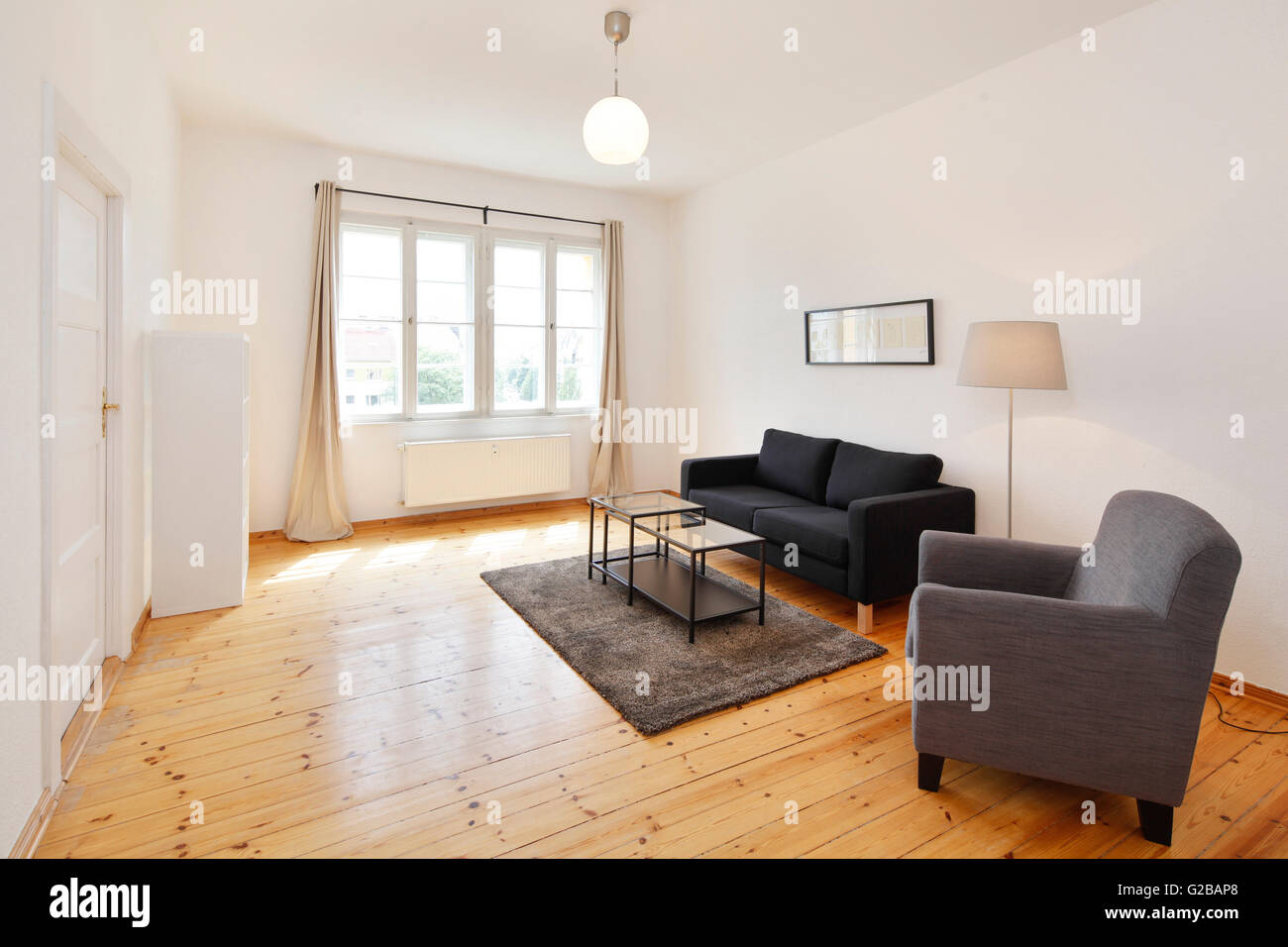 Wisbyer Strasse 59. Modern living with minimal furnishing and wood flooring. Large window. Stock Photo