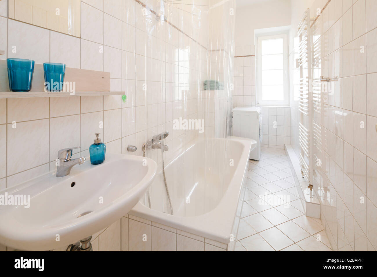 Wisbyer Strasse 59. Modern bathroom with white tiling and white features. Blue accessories. Stock Photo