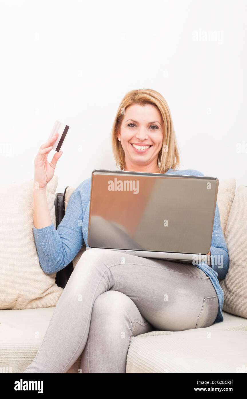 Single woman shopping online using credit card sitting on the couch or sofa Stock Photo