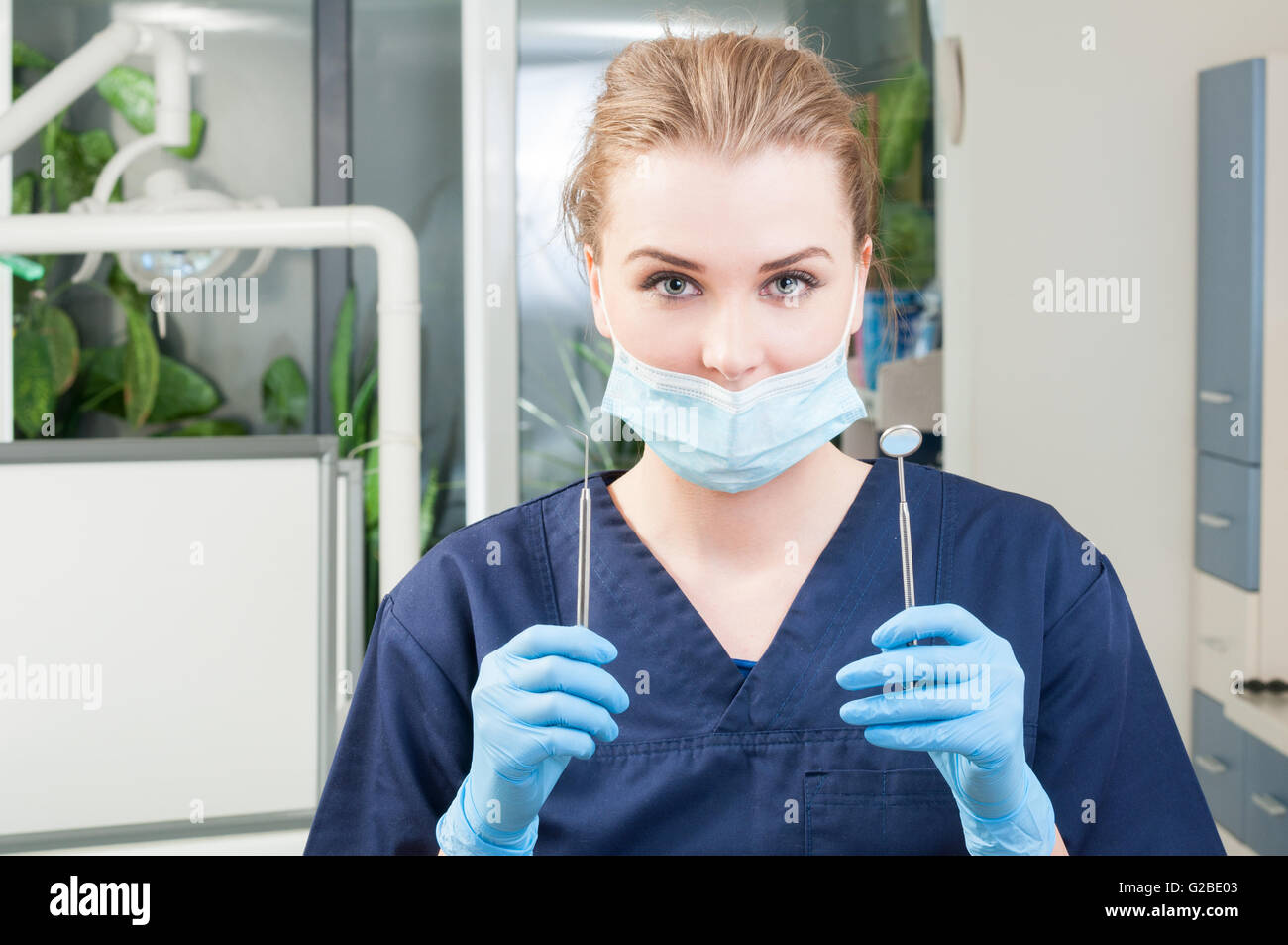 Portrait of young female dentist with tools in dental clinic wearing