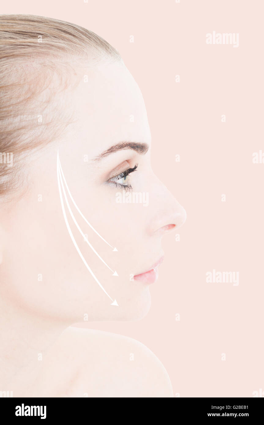 Close-up of woman face with lifting arrows on her cheek as facial beauty treatment and rejuvenation concept against pink backgro Stock Photo