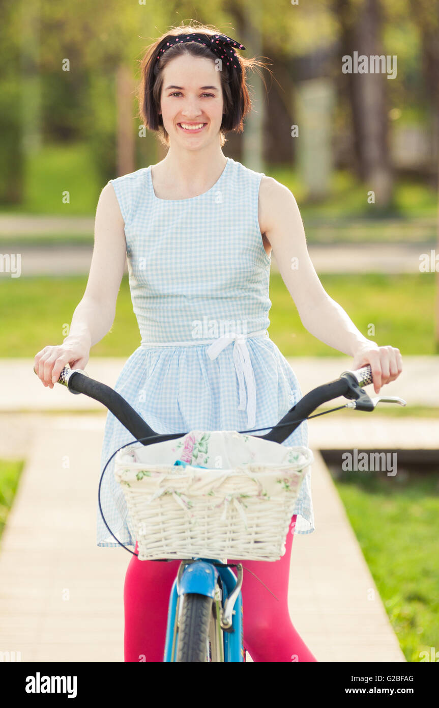 Portrait of joyful female riding a bicycle in the park and smiling ...