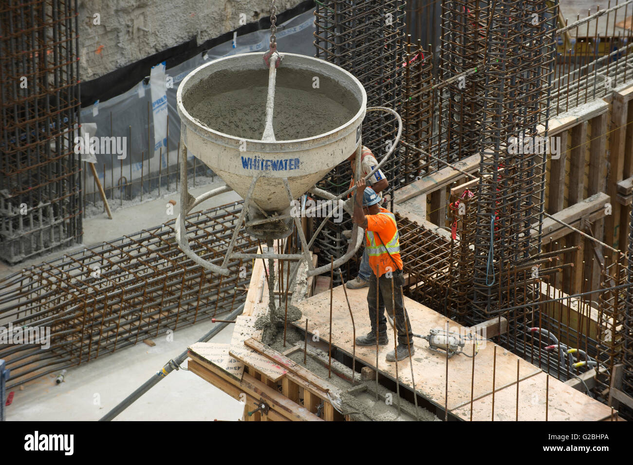 Construction workers directing a concrete hopper into position Stock