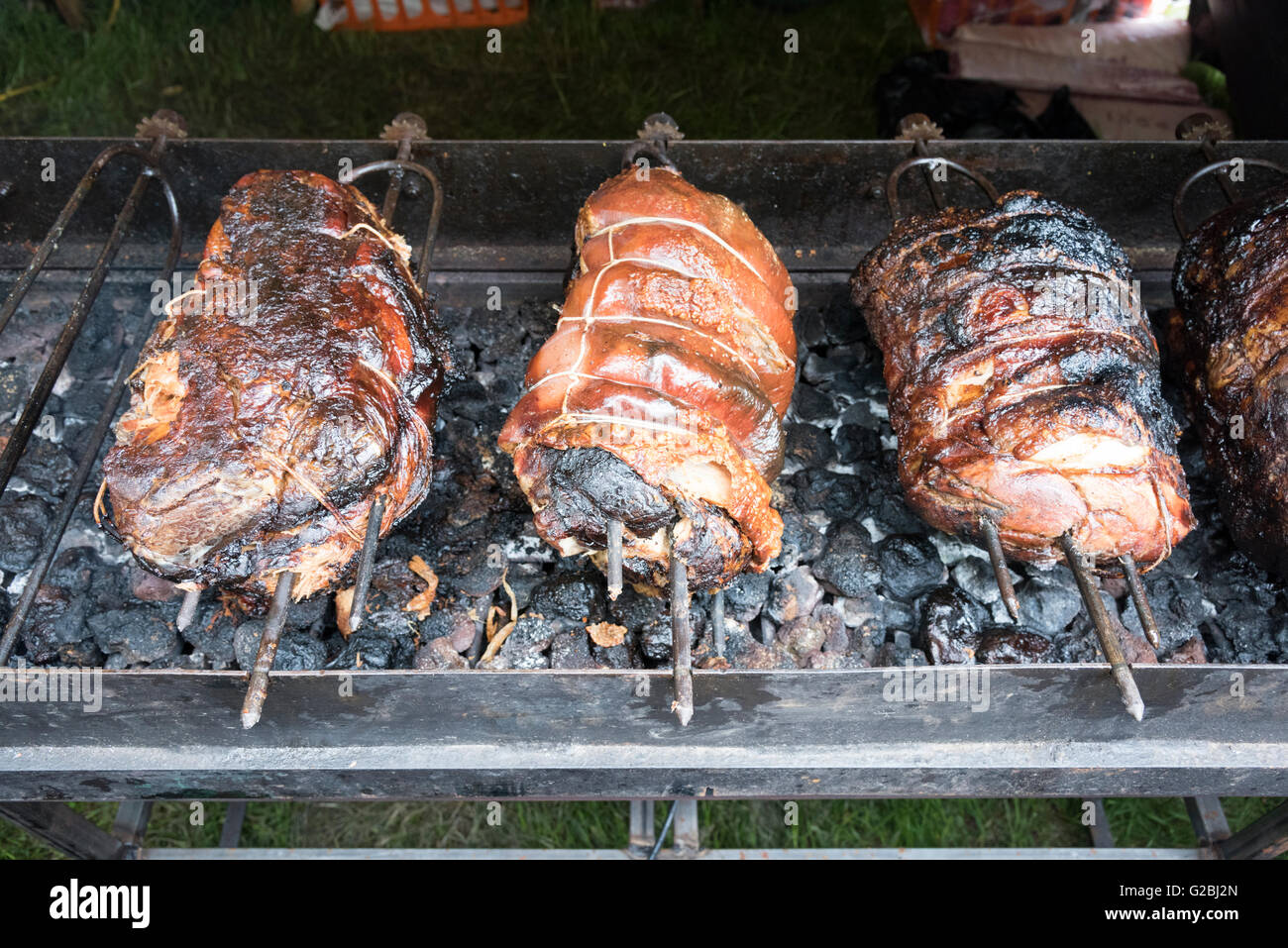 Joints of pork roasting on a spit over charcoal Stock Photo