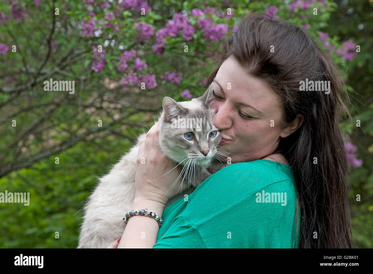 Woman kisses Siamese mix cat in springtime Stock Photo