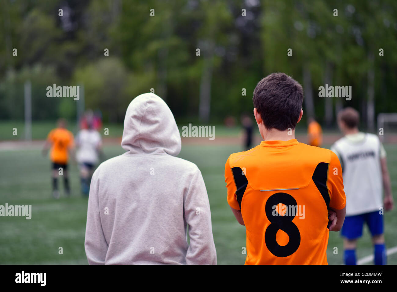 Fan and reserve player watch the student football match Stock Photo